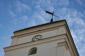 Wall Mural - Bottom view of an old stone clock tower with a weather vane against the blue sky