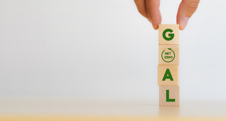 Wall Mural - Net zero goal and strategy concept. Decarbonization, low carbon economy for sustainable development. Hand put vertical wooden cubes with “GOAL” text and net zero icon on white background ,copy space