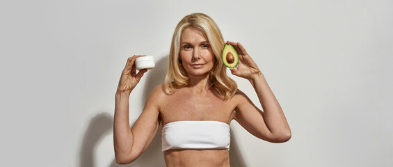 Wall Mural - Woman holding sliced avocado and cosmetic cream