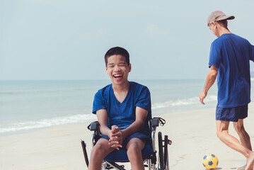 Wall Mural - Young man with disability playing ball on the beach, Practice small muscle skills and large muscles skills through with sport outdoor activity family, Natural therapy and mental health concept.