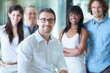 Wall Mural - The team that wins. Cropped shot of a businessman sitting in front of his colleagues in the office.