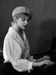 black and white portrait of a girl in a white shirt and beret playing the piano