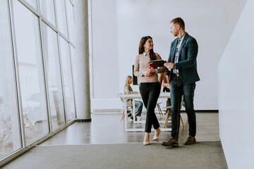 Young entrepreneur couple walking together and using digital tablet in the modern office