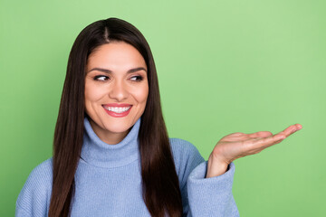 Poster - Photo of charming dreamy mature lady dressed blue pullover holding arm empty space smiling isolated green color background