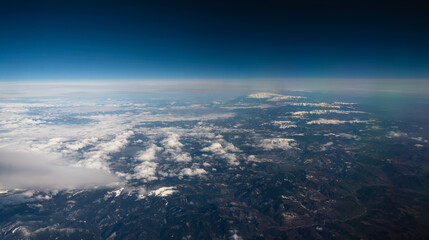 view from the airplane window to mountains clouds and blue sky