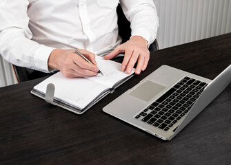 Poster - Hands taking notes, writing in planner at office desk with laptop.