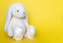 Stuffed Bunny On Yellow Background. Easter Concept. Cute White Toy Bunny Sitting On Colored Background.