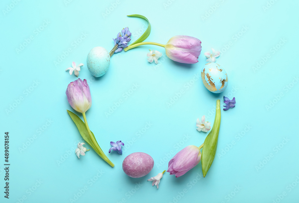 Stylish wreath with painted Easter eggs and beautiful flowers on blue background