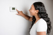 © Louis-Paul Photo - African woman lady adjusting the climate control panel on the wall wall thermostat