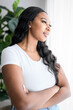 © Louis-Paul Photo - African American woman looking to aside out window, standing at home