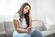 © Louis-Paul Photo - Attractive young African woman sitting on the couch at home stress with bill to pay