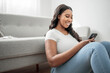 © Louis-Paul Photo - Attractive young African woman sitting on the couch at home with cellphone