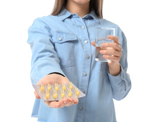 Wall Mural - Young woman with fish oil pills and glass of water on white background, closeup