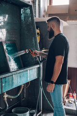 Wall Mural - Male worker cleaning screen frame with water in a printing workshop