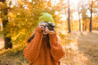 Young woman taking picture in autumn forest