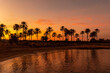 Silhouette of palm trees reflected in an orange sunset on a beach by the sea in the town of Torrevieja, Cala Ferris. White coast of the Mediterranean Sea of Alicante. Spain