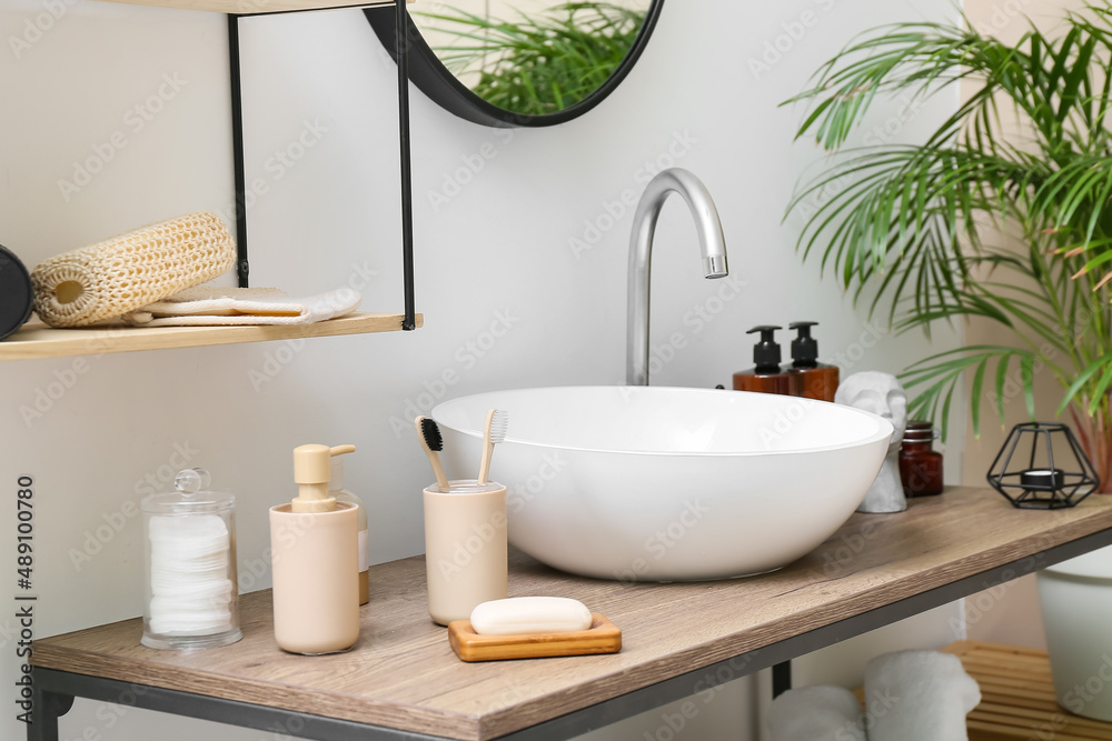 Bath supplies and modern sink on table near light wall