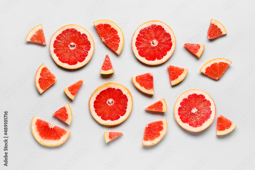 Slices of tasty ripe grapefruit on light background