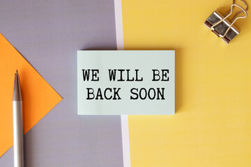 WE'LL BE BACK SOON text on notepad with laptop on the white background.