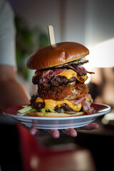 Canvas Print - A vertical closeup of the hand holding a plate with burger.