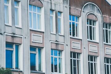 Facade of an old building with many windows. Exterior design of apartment building with ornamental details.