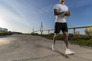 Poster - Strong muscular guy with cool tattoos jogging on a road