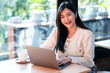 Portrait freelance business beautiful positive smile young asian woman online working with laptop computer and a coffee cup at home in the living room indoors or the cafe,Business Lifestyle