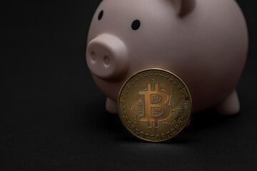 Pink piggy bank and bitcoin coin on a black background. The future of virtual money currency, account security, investment in cryptocurrency.