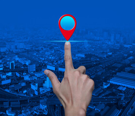 Hand pressing map pin point location button over modern city tower, street, expressway and skyscraper, Map pointer navigation concept