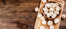 Mushrooms In A Bowl On A Cutting Board. On A Wooden Background. High Quality Photo