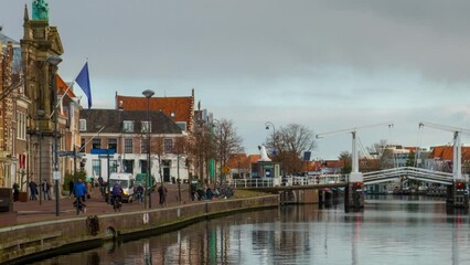 Wall Mural - Haarlem, Netherlands. View of the city center in Haarlem, Netherlands during a cloudy winter day. Time-lapse of the river with people and car traffic, panning video