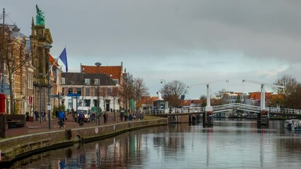 Wall Mural - Haarlem, Netherlands. View of the city center in Haarlem, Netherlands during a cloudy winter day. Time-lapse of the river with people and car traffic