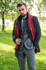 Wall Mural - A man in a business suit and coat poses on a spring walk
