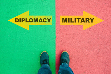 Wall Mural - Diplomacy or Military choice, text on asphalt ground, feet and shoes on floor