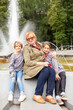 © DariaTrofimova - Old woman hugging  granddaughters at fountain in   park