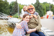 © DariaTrofimova - Old woman hugging  granddaughters at fountain in   park