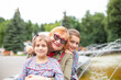 © DariaTrofimova - Old woman hugging  granddaughters at fountain in   park