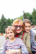 © DariaTrofimova - Old woman hugging  granddaughters at fountain in   park