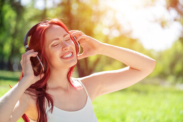 Canvas Print - Young woman happens to have music in a summer park