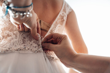 Poster - A closeup shot of female hands zipping up the wedding dress on a bride