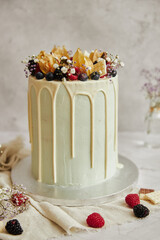 Wall Mural - Vertical closeup shot of a drip cake with fruits on top of it on a  white table and background