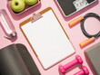 Stylish workout plan mockup in gray and pink colors. Fitness training flat lay. Top view of sport equipment, water bottle, scales and empty white sheet on clipboard on pink background. Copy space