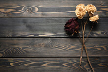 Dry rose flowers on the wooden desk table flat lay background with copy space.