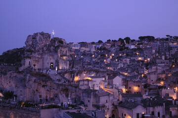 Wall Mural - Scenic view of an old cityscape with city lights and people walking by the streets