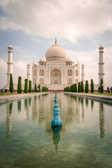 Canvas Print - Beautiful view of the famous Taj Mahal and bushes around water against a light blue sky