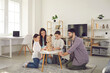 © Studio Romantic - Happy family with kids playing board games at home. Smiling mom, dad and children sitting on the floor around a low table in a cozy living room and pulling wooden blocks from the tower