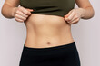 © Марина Демешко - Cropped shot of a young slender woman with toned stomach with abs isolated on a beige background. Result of fitness, diet, healthy lifestyle. Female belly after a lot of training. Lines and six-packs