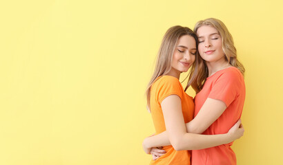 Canvas Print - Portrait of happy young sisters on color background