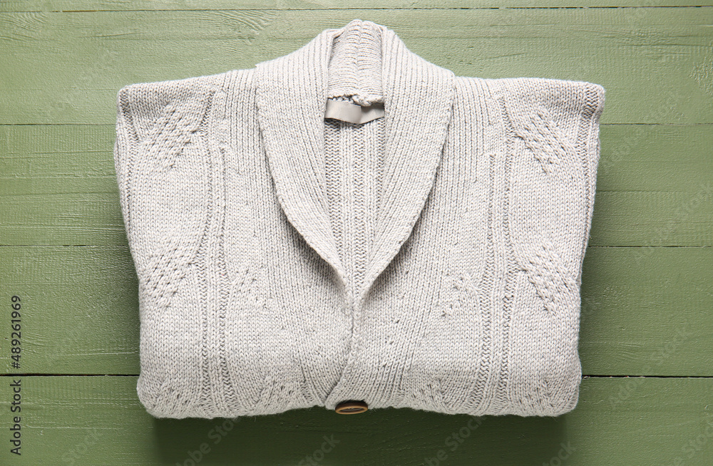 Stylish sweater on color wooden background