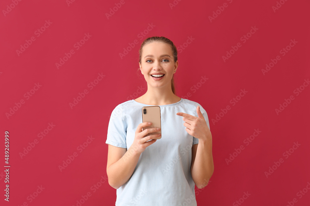 Pretty young woman with mobile phone on red background